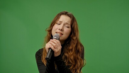 Teenage girl posing at camera smiling and singing song in karaoke microphone, positive expression,...