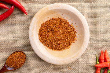 traditional kitchen spices. fresh chili powder on a wooden plate lined with burlap