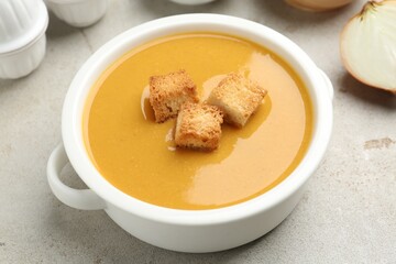 Delicious lentil cream soup with croutons on light grey table, closeup
