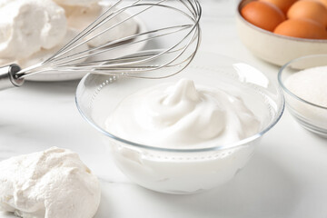 Whisk, whipped cream in bowl and other ingredients on light table, closeup. Cooking meringue cookies