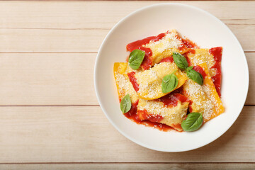 Delicious ravioli with tomato sauce, parmesan cheese and basil on white wooden table, top view. Space for text