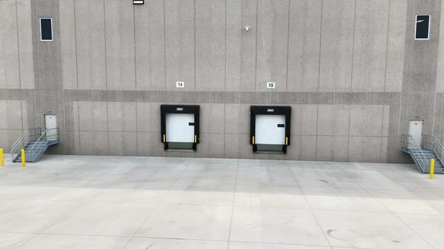 Close-up view of loading docks at a warehouse, with dock doors, ramps, and trailers positioned for freight handling. The scene represents the logistics core of supply chain operations and efficient go