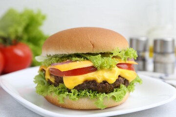 Tasty cheeseburger with lettuce and tomatoes on white table, closeup