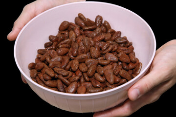 raw cocoa beans in plastic bowl