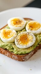 Avocado Toast with Sliced Egg Topped with Pepper on a White Plate Close Up View