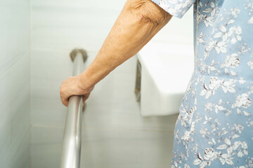 Asian elderly old woman patient use toilet support rail in bathroom, handrail safety grab bar, security in nursing hospital.