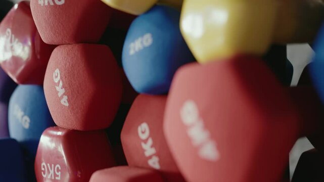 A variety of colorful dumbbells, including 2kg and 4kg weights, stacked in a gym setting, ideal for strength training and fitness routines. Colorful Dumbbells Weighing