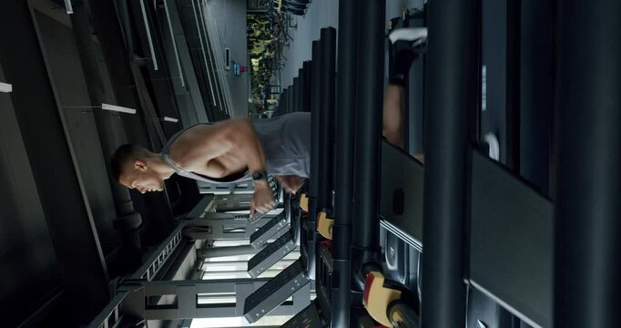 An athletic man intensely works out on a rowing machine, showcasing his focus and strength in a state-of-the-art gym setting. Focused Athlete Working Out on Rowing Machine in Modern Gym. Vertical