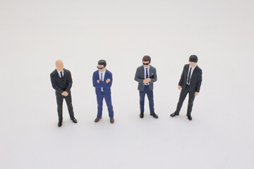 Fototapeta premium Four Miniature Business Figures Standing in Group Formation