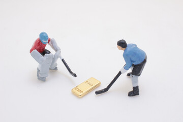 Miniature Ice Hockey Players Battling Over a Golden Bar