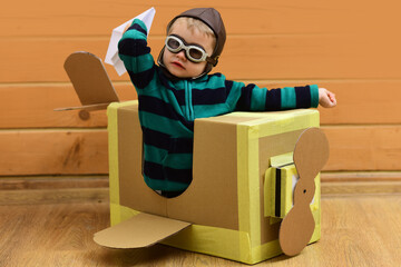 Kid play with imagined wings. Imaginative child dreams of flying. Cardboard wings spark imagination play. Creative kid play pilot. Kids play with imagination. Children playing with toy plane at home.