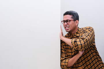 A man pushing a blank white wall with full of effort