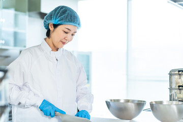 厨房で料理する衛生白衣を着た女性調理師　給食センター　給食室