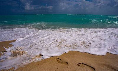 Foot steps on sand. Sea waves. Summer background. Ocean water motion. Ocean splash wave background. Deep blue sea beach. Turquoise wave background. Dreamy exotic sea beach background.