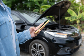 breakdown, broken car, repair. Woman uses mobile phone check insurance premiums through application...