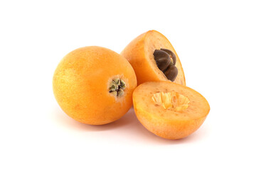 A collection of ripe loquats, with one cut to reveal the seeds, set on a bright white backdrop.