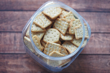 Crunchy crackers arranged in a clear container on wooden surface