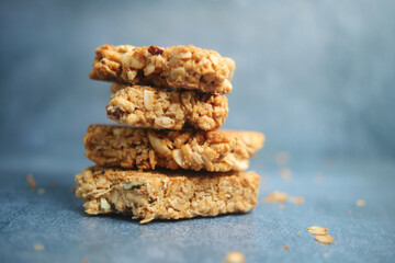 Granola bars stacked on a blue background with scattered ingredients