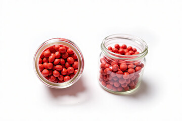 Two Glass Jars of Red Granules on White Background





