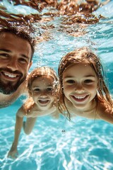 A father and his two daughters smile at the camera while submerged in a pool