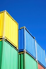 Obraz premium Colorful shipping containers stacked against a clear blue sky creating a vibrant urban landscape for logistics and transportation themes