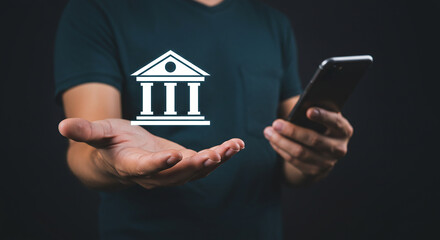 A person holding a phone with a bank icon hovering above their hand on a dark background scene setup real estate business ,technology ,selling ,purchasing ,agreement ,$