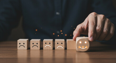 Person selecting happy face wooden block from row of sad face blocks on a wooden surface table real estate business ,technology ,selling ,purchasing ,agreement ,$