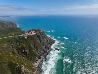 Elevated view of dramatic cliffs and coastal buildings beside ocean