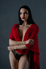 Elegant woman in striking lingerie with flowing red fabric in a studio setting