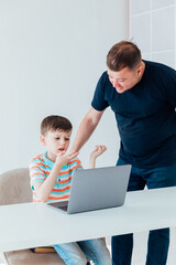 Teacher Teaches Boy Schoolboy At Table With Laptop Online
