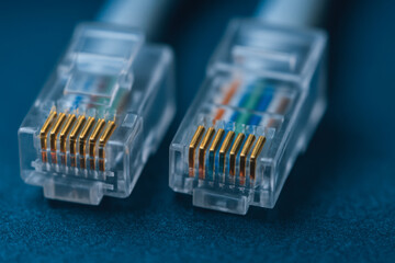 Two transparent network cables with gold connectors lie blue surface symbolizing industrial power plant communication technology and connectivity