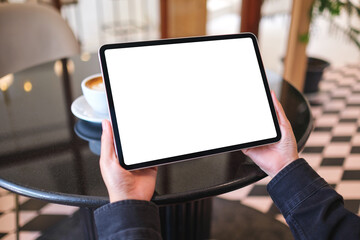 Mockup image of a woman holding digital tablet with blank white desktop screen in cafe