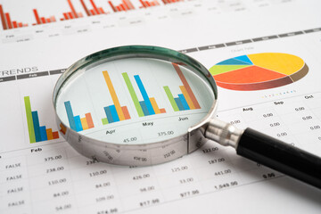 Magnifying glass on spreadsheet and graph paper. Financial data economy, Business.