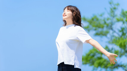 夏の青空と深呼吸をする笑顔の女性