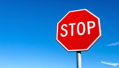 Obraz premium 一時停止の標識。澄み切った青空と山々がそびえる高原地帯の直線道路沿いにあるストップの道路標識。A stop sign. A stop road sign along a straight road in a plateau area with clear blue skies and towering mountains.