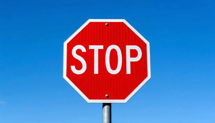 Obraz premium 一時停止の標識。澄み切った青空と山々がそびえる高原地帯の直線道路沿いにあるストップの道路標識。A stop sign. A stop road sign along a straight road in a plateau area with clear blue skies and towering mountains.