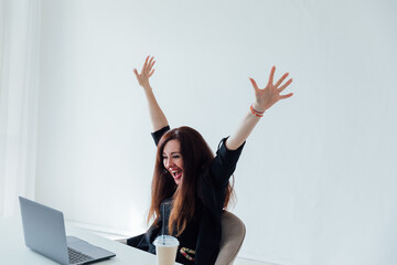 woman working on a table with a laptop happily laughing