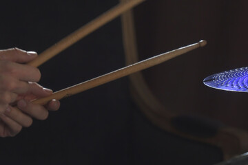 Hands hold the drumsticks while playing