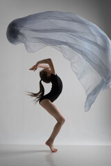A girl in a swimsuit and a dress shows beautiful athletic elements on a white background. Ballet, rhythmic gymnastics, fabric, aesthetics, grace