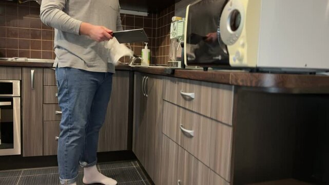 A man in the kitchen carefully wipes a clean meat cleaver with a cloth, preparing it for cooking.