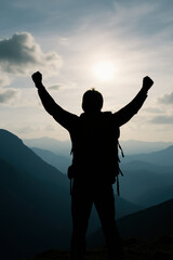 Fototapeta premium Silhouette of hiker with arms raised against a mountain and sky view
