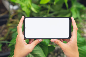 Hand holding smartphone with blank screen for graphic display montage on outdoors background, mockup display for lifestyle and wireless technology.