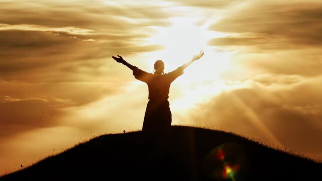 Woman Silhouetted Against a Vibrant Sunset Sky Rejoicing on Hilltop