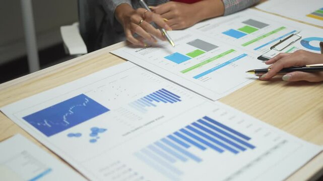 Two people are looking at a table with several graphs and charts. They are discussing the data and trying to understand the trends and patterns. The atmosphere seems to be focused and analytical