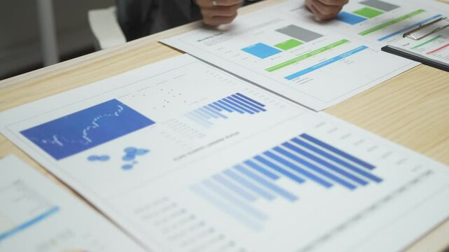 A table with several graphs and charts on it. The graphs are of different sizes and colors, and they all seem to be related to some kind of data analysis. Scene is serious and focused