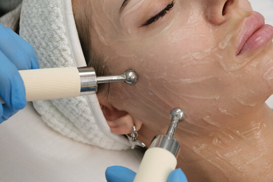 Close-up of performing a microcurrent therapy facial rejuvenation treatment to a client in a beauty clinic. Doctor uses electrical pulses for cosmetic procedures enhancing skin appearance