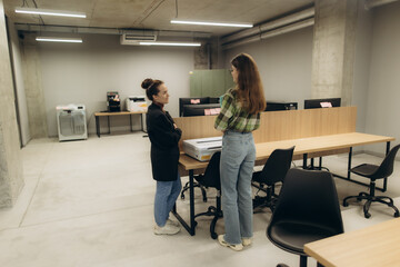 Two Businesswomen Engaged in Discussion in a Modern Open Workspace