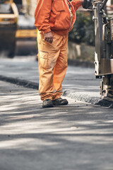 Construction workers working on a new asphalt layer on a public street.