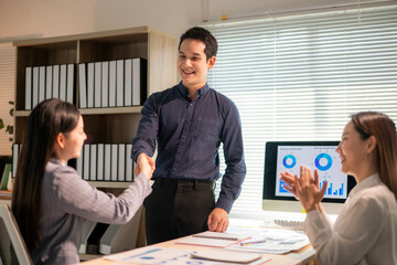 A man shakes hands with two women