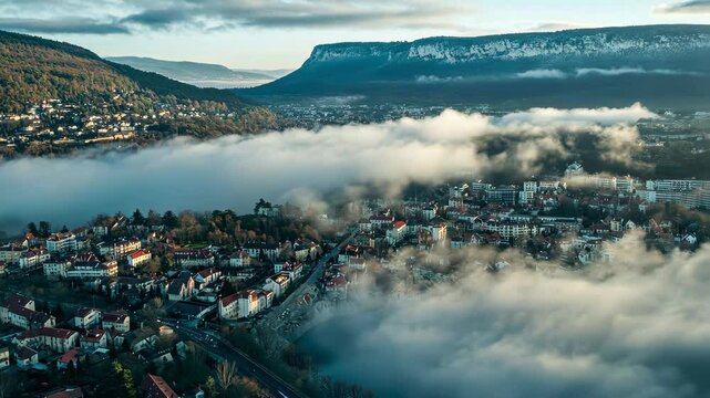 Clouds and tranquility envelop the city of Ambrieu-en-Bugey during early morning hours in France, Aerial view around the city Amb&Atilde;&copy;rieu-en-Bugey in France on a low cloud afternoon in late winter